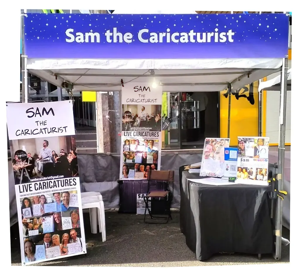 Sam the Caricaturist's market stall with banners and a blue canopy