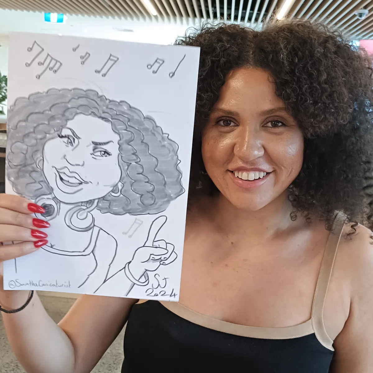 Smiling guest with curly hair holding up her caricature